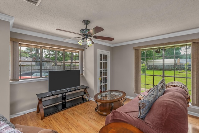 living area with crown molding, ceiling fan, plenty of natural light, a textured ceiling, and wood finished floors