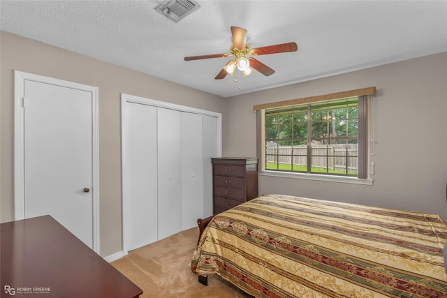 bedroom with carpet, a closet, a ceiling fan, and a textured ceiling