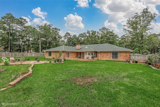 rear view of property with brick siding, a chimney, view of scattered trees, and a patio area