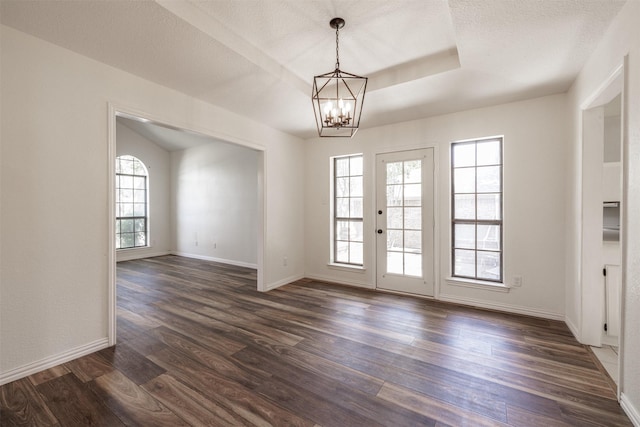 unfurnished room featuring a chandelier, dark wood-style flooring, and baseboards