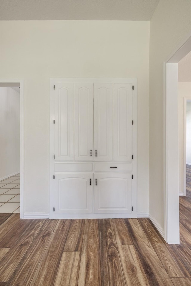 unfurnished bedroom with wood finished floors, baseboards, and a closet