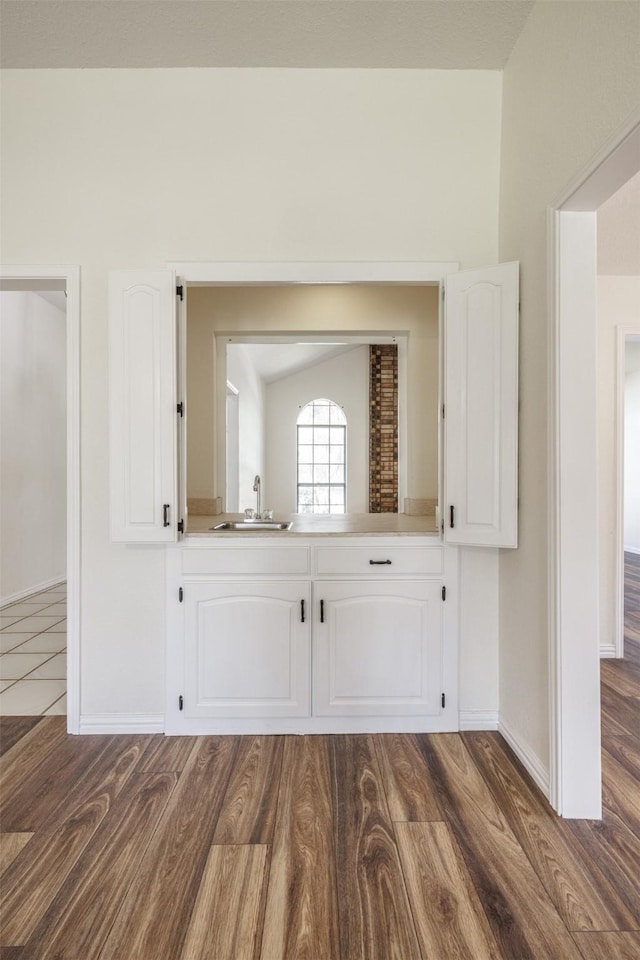 detailed view of a sink, wood finished floors, and baseboards