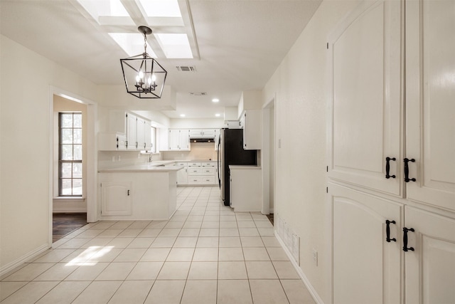 kitchen with a chandelier, a skylight, light tile patterned floors, baseboards, and light countertops
