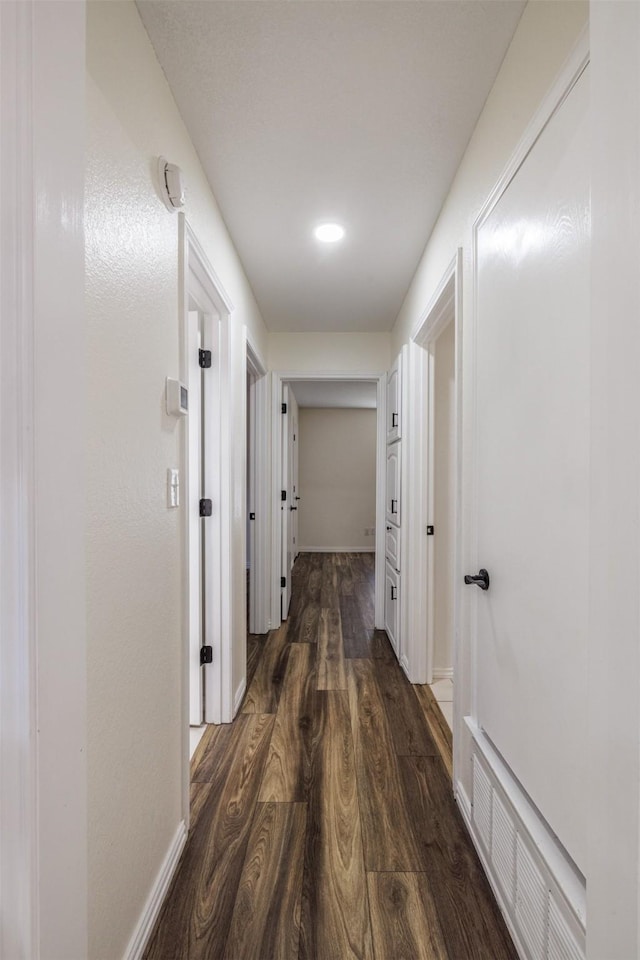 hallway with dark wood-style floors and baseboards