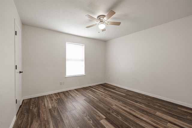 empty room with dark wood-style floors, a ceiling fan, and baseboards