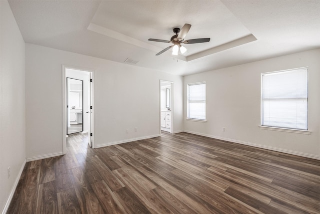 unfurnished room with a raised ceiling, ceiling fan, dark wood-style floors, and baseboards