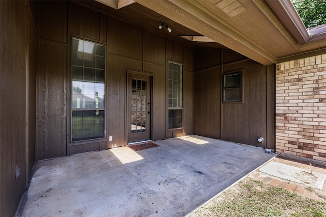 view of exterior entry with brick siding and a patio area