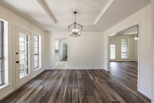 unfurnished dining area featuring dark wood-style flooring, a chandelier, and baseboards