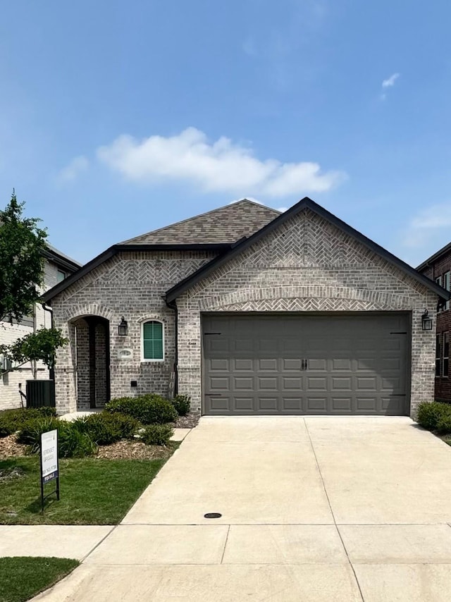 1812 Horseshoe Ln, Van Alstyne, TX 75495 - french provincial home featuring a garage, concrete driveway, brick siding, and central AC