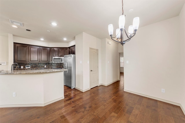7941 Parkwood Blvd, Plano, TX 75024 - kitchen with stainless steel appliances, dark brown cabinetry, a chandelier, dark wood-style flooring, and light stone countertops