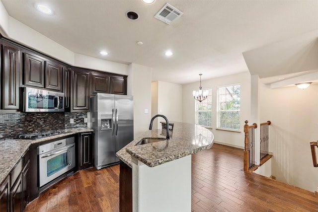 7941 Parkwood Blvd, Plano, TX 75024 - kitchen with stainless steel appliances, a sink, dark wood-type flooring, light stone countertops, and a chandelier