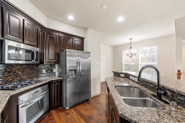 7941 Parkwood Blvd, Plano, TX 75024 - kitchen featuring appliances with stainless steel finishes, a sink, a chandelier, dark wood-style floors, and decorative backsplash