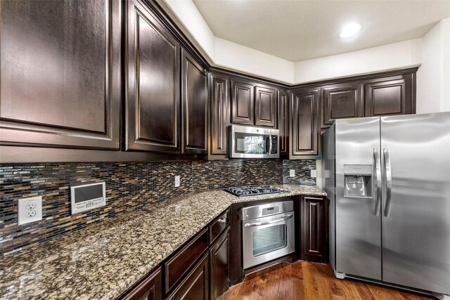 7941 Parkwood Blvd, Plano, TX 75024 - kitchen featuring stainless steel appliances, dark wood-style floors, stone countertops, dark brown cabinetry, and decorative backsplash