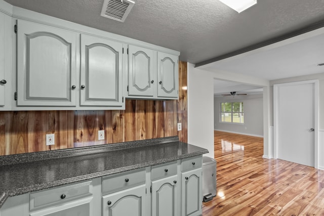 560 N Cardinal Rd, Reno, TX 76020 - kitchen with dark countertops, light wood finished floors, a textured ceiling, ceiling fan, and wooden walls