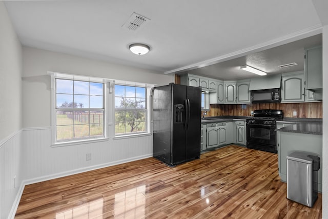 560 N Cardinal Rd, Reno, TX 76020 - kitchen with black appliances, dark countertops, wood finished floors, a wainscoted wall, and gray cabinets