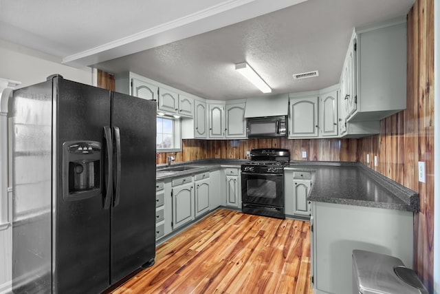 560 N Cardinal Rd, Reno, TX 76020 - kitchen with black appliances, dark countertops, a sink, light wood-style floors, and a textured ceiling