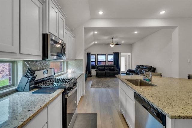 716 Newberry Ln, Royse City, TX 75189 - kitchen with stainless steel appliances, vaulted ceiling, a sink, light wood-style flooring, and decorative backsplash