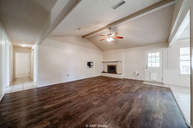 3226 Whitewing Way, Abilene, TX 79606 - unfurnished living room featuring wood finished floors, a ceiling fan, a fireplace with raised hearth, and a textured ceiling