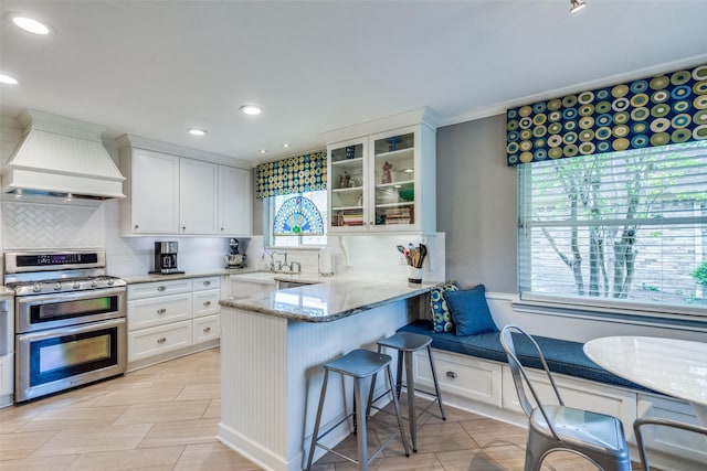 1835 Hatherly Dr, Plano, TX 75023 - kitchen with range with two ovens, custom exhaust hood, a sink, backsplash, and white cabinetry