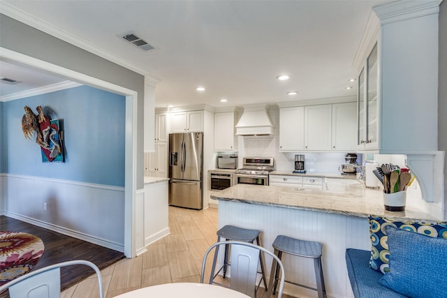 1835 Hatherly Dr, Plano, TX 75023 - kitchen with appliances with stainless steel finishes, premium range hood, light stone counters, white cabinets, and light wood-type flooring