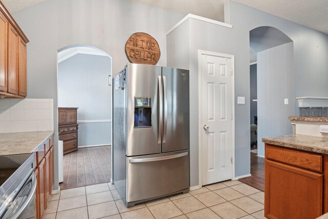 5729 Brazos Dr, Haltom City, TX 76137 - kitchen with appliances with stainless steel finishes, arched walkways, light tile patterned floors, tasteful backsplash, and a textured ceiling