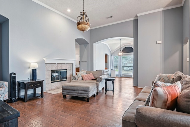 5729 Brazos Dr, Haltom City, TX 76137 - living room featuring arched walkways, dark wood finished floors, a tiled fireplace, lofted ceiling, and baseboards