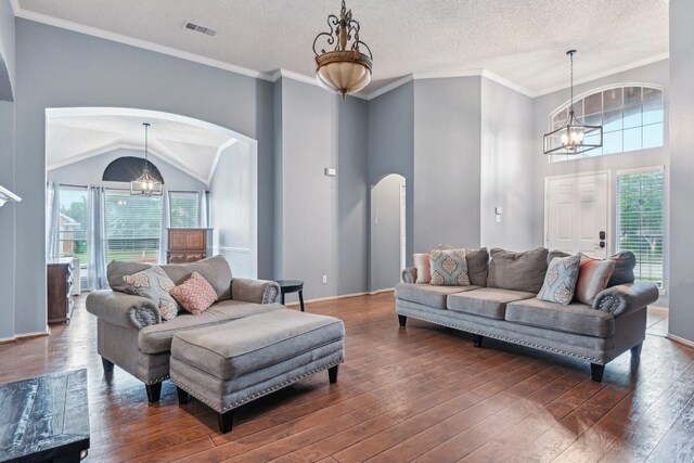 5729 Brazos Dr, Haltom City, TX 76137 - living area with arched walkways, healthy amount of natural light, dark wood-type flooring, a chandelier, and a textured ceiling