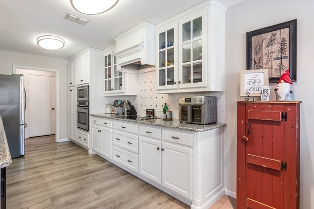 332 Azalea Dr, Sulphur Springs, TX 75482 - kitchen featuring appliances with stainless steel finishes, white cabinetry, light wood finished floors, light stone counters, and glass insert cabinets