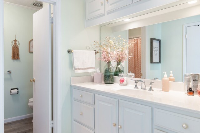 332 Azalea Dr, Sulphur Springs, TX 75482 - bathroom with vanity, wood finished floors, toilet, baseboards, and crown molding