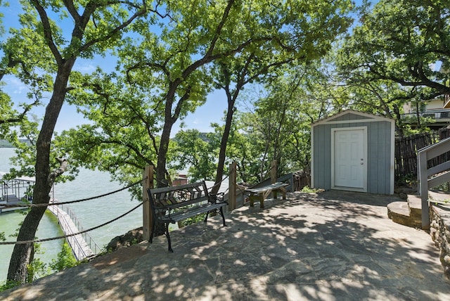 306 Chism Trl, Gordon, TX 76453 - view of patio / terrace featuring a shed, a water view, an outbuilding, and fence