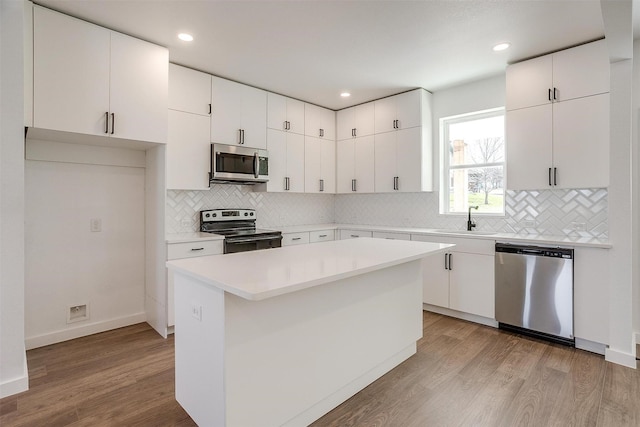 171 Tryall Ct, Runaway Bay, TX 76426 - kitchen with appliances with stainless steel finishes, a sink, light wood-type flooring, white cabinets, and recessed lighting