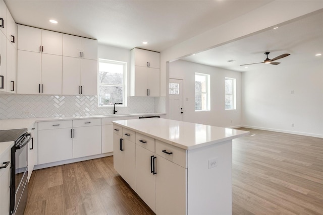 171 Tryall Ct, Runaway Bay, TX 76426 - kitchen with black / electric stove, light wood-type flooring, decorative backsplash, a center island, and a sink