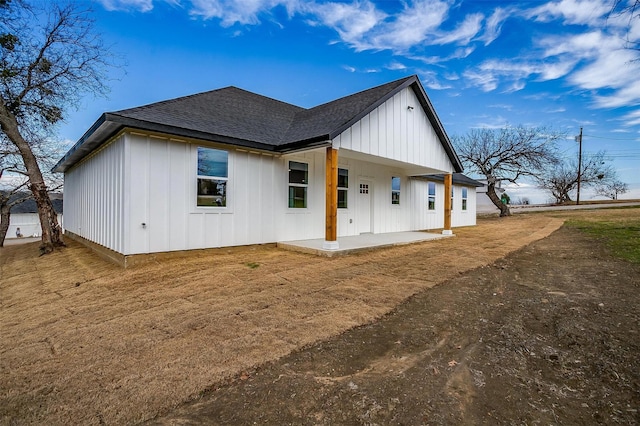 171 Tryall Ct, Runaway Bay, TX 76426 - back of house with board and batten siding, roof with shingles, a patio area, and dirt driveway