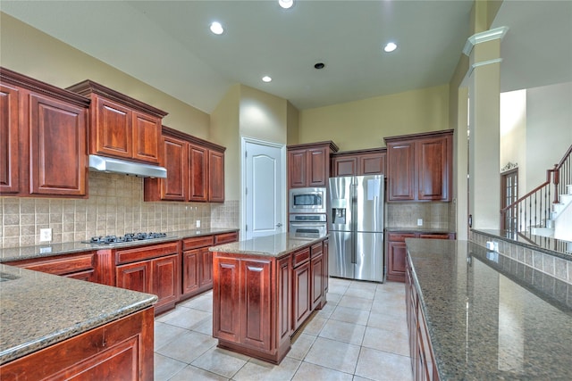 319 Paloverde Ln, Frisco, TX 75036 - kitchen featuring appliances with stainless steel finishes, under cabinet range hood, decorative backsplash, dark stone counters, and light tile patterned floors