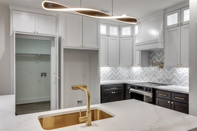 2614 Ave G, Fort Worth, TX 76105 - kitchen featuring stainless steel electric range, a sink, white cabinetry, tasteful backsplash, and glass insert cabinets