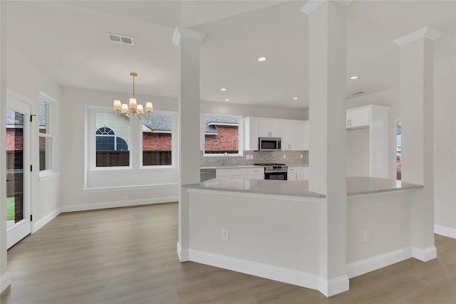 1529 Harvest Run Dr, Allen, TX 75002 - kitchen with stainless steel appliances, white cabinetry, light countertops, light wood-type flooring, and a chandelier