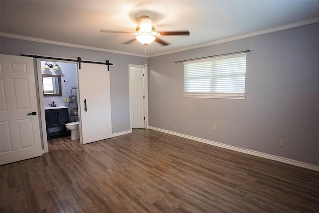 1413 Oak Hills Dr, Graham, TX 76450 - unfurnished bedroom featuring a barn door, dark wood-type flooring, a sink, multiple windows, and crown molding