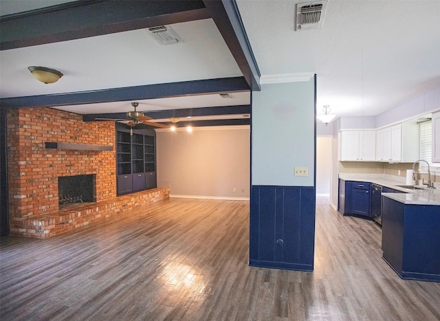 1413 Oak Hills Dr, Graham, TX 76450 - unfurnished living room featuring a sink, a ceiling fan, wood finished floors, a brick fireplace, and beam ceiling