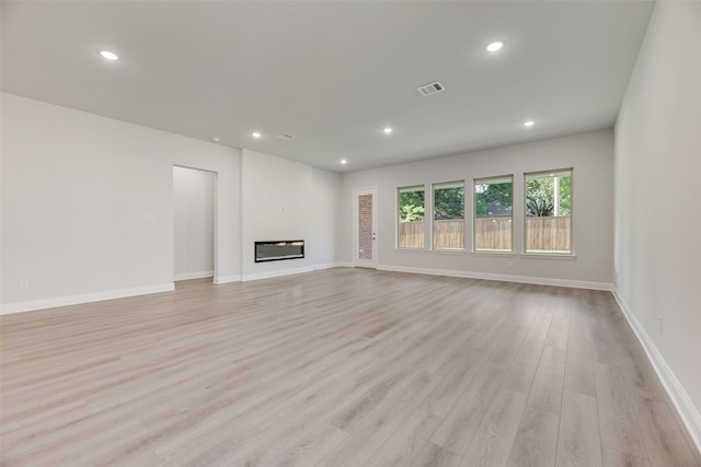 7111 Manhattan Dr, Rowlett, TX 75088 - unfurnished living room featuring light wood-style floors, recessed lighting, baseboards, and a glass covered fireplace