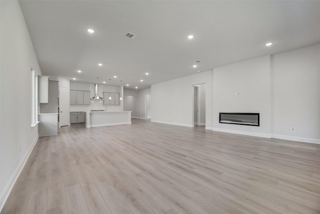 7111 Manhattan Dr, Rowlett, TX 75088 - unfurnished living room with light wood-style floors, recessed lighting, baseboards, and a glass covered fireplace