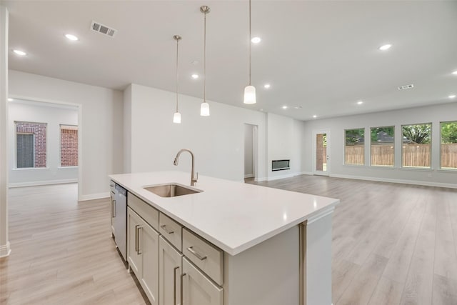 7111 Manhattan Dr, Rowlett, TX 75088 - kitchen with a sink, light wood-style flooring, light countertops, open floor plan, and a center island with sink