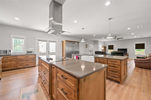 12570 County Road 313, Tyler, TX 75708 - kitchen featuring an island with sink, wall chimney range hood, stainless steel appliances, brown cabinets, and ceiling fan
