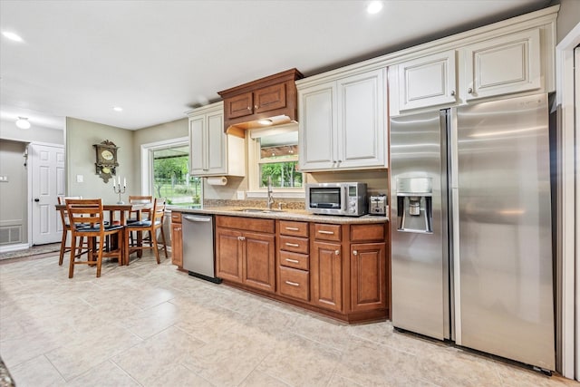 635 Old Justin Rd, Argyle, TX 76226 - kitchen featuring appliances with stainless steel finishes, a sink, light stone counters, recessed lighting, and brown cabinetry
