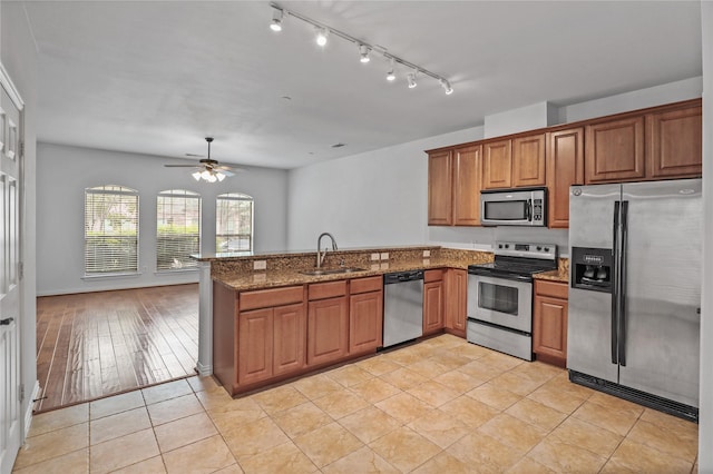 5719 Butterfly Way, Fairview, TX 75069 - kitchen featuring appliances with stainless steel finishes, a peninsula, brown cabinets, dark stone countertops, and ceiling fan