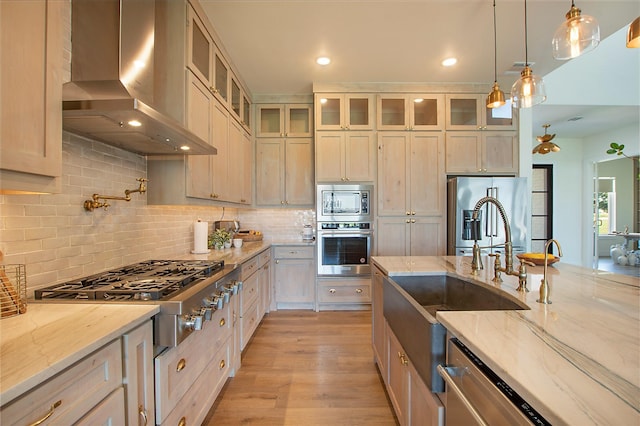 10356 Wild Rose Cir, Forney, TX 75126 - kitchen with appliances with stainless steel finishes, wall chimney range hood, a sink, light stone counters, and decorative backsplash