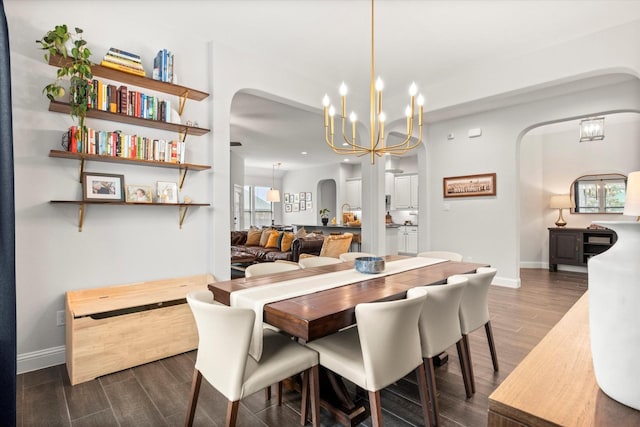 dining room featuring arched walkways, dark wood finished floors, a chandelier, and baseboards