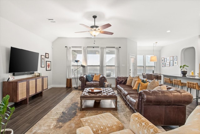 living area featuring dark wood-type flooring, ceiling fan, baseboards, arched walkways, and recessed lighting