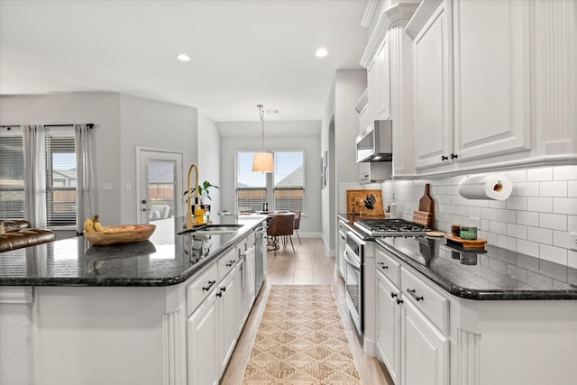 kitchen featuring appliances with stainless steel finishes, white cabinetry, decorative backsplash, a center island with sink, and recessed lighting