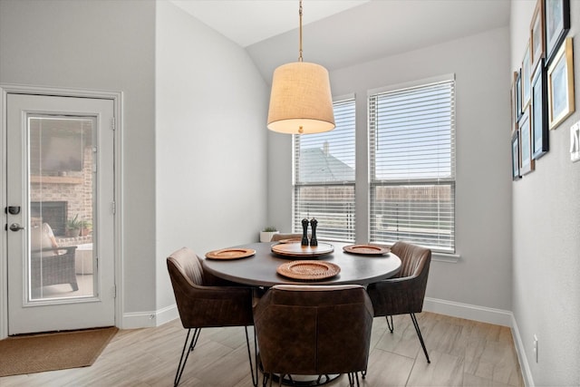 dining room with light wood finished floors, baseboards, and lofted ceiling