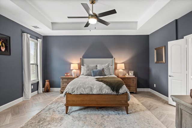 bedroom featuring a tray ceiling, baseboards, and ceiling fan